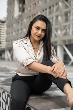 Güneşli bir günde düz saçlı, resmi bir bluz, moda ve güzellik giyen genç Latin bir kadın var.