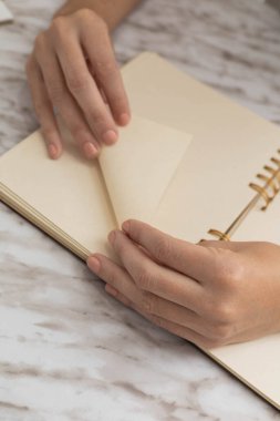 Not defterindeki kağıtları katlamak, origami yapmak, yaratıcı ve sanatsal aktivite, stüdyodaki kırtasiye eşyalarının ayrıntıları.