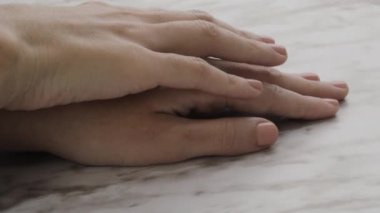 Stüdyoda kısa tırnakları ve ojeli doğal rengi, manikürü ve güzelliği olan, dokulu arka planı olan birinin ellerine kişisel bakım ve hijyen.