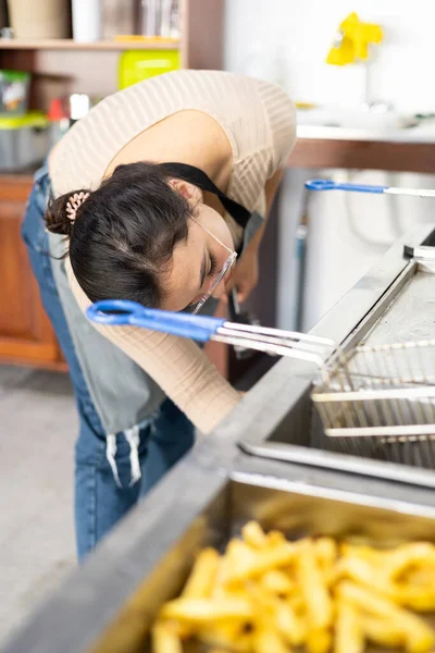 young woman working, turning on an industrial kitchen for fast food, workplace lifestyle, housework