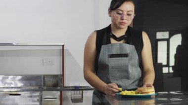 Güzel genç bir kadın patates kızartması yiyor, fast food tadıyor, hamburger tabağı yiyor, mutfakta temizlik yapıyor.