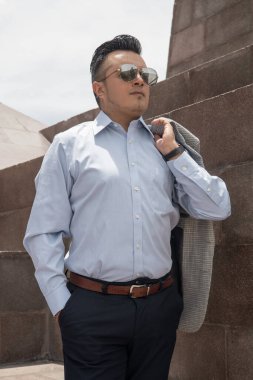 Kısa saçlı, gömlek, ceket, güneş gözlüğü, şık kıyafetler ve göz kamaştırıcı bir hayat süren genç bir adamla güneşli bir gün.