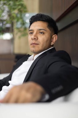 Rahat bir erkek modelin resmi kıyafetler ve iş hayatı tarzıyla göz kamaştırıcı bir yaşam tarzı. Kısa saçlı, portresi, geçmişi olan genç bir Latin.