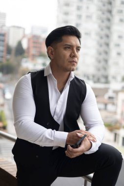 Kısa saçlı, şehirde yelek ve gömlek giyen bir genç adamın doğal güzelliği. Erkek model yaşam tarzı, Latin insan portresi, resmi moda.