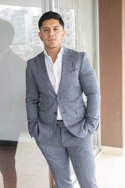 Kısa saçlı, gri takım elbiseli ve tişörtlü çekici bir genç adam, resmi bir iş adamı giysisi ve yaşam tarzı, güneş ışığıyla portresi