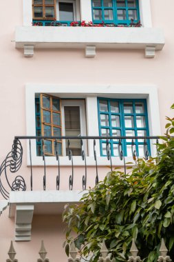 Siyah demir pervazlı, balkonlu pembe bir bina. Yumuşak pembe dış ve zarif siyah demirin kombinasyonu...