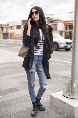 Güzel bir kız telefonuna sakin ve odaklanmış bir ifadeyle cevap veriyor. Doğal güzelliği ve zahmetsiz stili kendini gösterirken... 