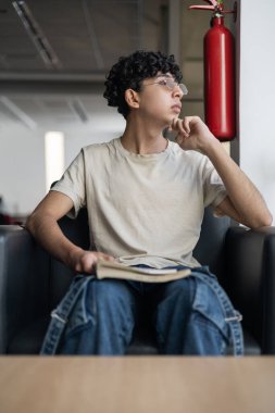 Pencereden dışarı bakan genç bir çocuk, derin düşünce ve tefekkür içinde. Farkındalık, meditasyon ve içgözlem konuları için mükemmel..