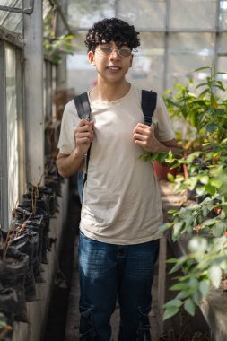 Rahatlamış ve sırt çantası taşıyan genç bir insan botanik bahçesinin huzurlu atmosferinin tadını çıkarıyor. Doğa, sağlık ve gençlik yaşam tarzı konuları için ideal..