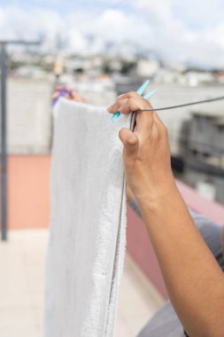 Güneşin altındaki çamaşır ipine temiz havlu asan bir insan ev, çamaşır ve açık hava yaşam temaları için mükemmel..