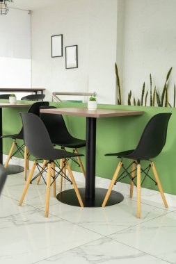 Siyah sandalyelerin ve kahve renkli masaların yer aldığı modern bir ofis kafesi, çalışmak ve rahatlamak için şık ve rahat bir yer sunuyor..