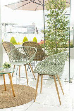 Zarif sandalyeleri ve modern şemsiyesi olan bir binada şık bir teras, rahatlama ve keyif için sofistike bir açık hava alanı yaratıyor..