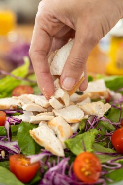 Nazikçe seçilen hassas, iyi baharatlı ızgara tavuk şeritleri canlı bir salata, kiraz domatesleri ve kırmızı lahana karışımı üzerinde rafine ve sağlıklı bir yemek yaratıyor..