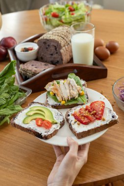 Üçlü leziz tost, her biri kremalı peynir tabanlı: biri olgun domates dilimleri, diğeri taze avokado ve sonuncusu taze tavukla kaplı. Dengeli ve tatmin edici bir yemek için basit ama lezzetli bir seçim..