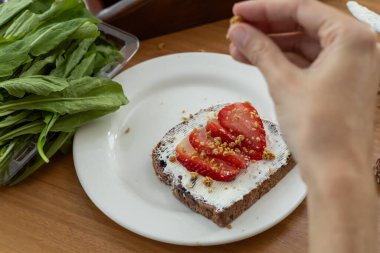 Lezzetli, krem peynirle kaplı basit bir tost, taze domates dilimleri, ve bir tutam keklik otu, günün her anı için mükemmel, lezzetli bir ısırık oluşturur..