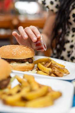 Patates kızartmasının üzerine sıkılmış ketçap ve yanında leziz bir hamburger, gündelik yemek keyfi ruhunu yakalıyor..