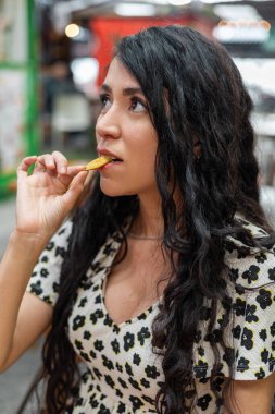 Güzel bir kadın gevrek bir kızartmayı ısırır. Yüzü basit ama tatmin edici bir fast food anında zevk verir..