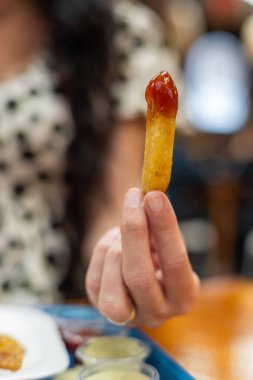 Bir el, çıtır bir kızartmayı ketçapla kaldırır, bir anlık zevk ve fast food düşkünlüğüyle ağzına doğru getirir..