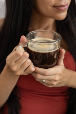 Genç bir kadının elleri yavaşça kahve fincanını tutarken, sakin ve sakin bir atmosferde sıcaklık ve sükunet yayarken..