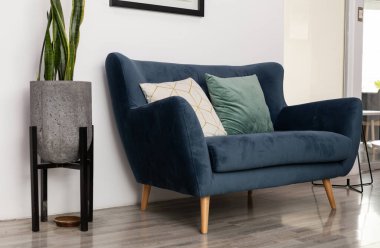 Modern bekleme salonunda şık bir mavi kanepe ve zarif bir dekoratif tencere var. Zarif bir dokunuşla misafirperver ve çağdaş bir ortam oluşturuyor..