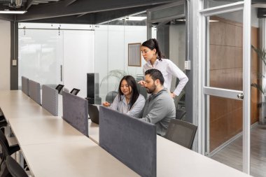 Üç iş arkadaşı, yurtdışından bir müşteriyle görüntülü görüşme yoluyla bağlantı kuruyor. Parlak bir ofis alanında ilişki ve profesyonellik gösteriyor..