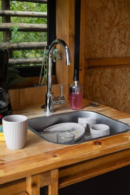 Mutfak lavabosuna istiflenmiş kirli tabaklar ve çatal bıçaklar. Görüntü, yoğun bir ev mutfağında yemek pişirmenin ve yemek yemenin gerçekçi sonuçlarını yakalıyor..