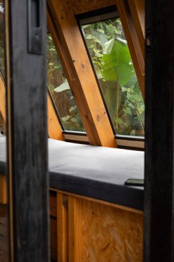 Odundan yapılmış, yumuşak doğal ışığı içeri alan bir pencereye sahip kırsal bir kulübe duvarının iç manzarası. Açığa çıkan yapı sıcaklığı ve el yapımı cazibeyi yaratır..