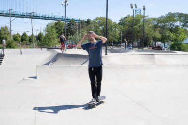 Patenciler ve motorcular numaralarını güneşli bir yaz gününde halka açık olan açık bir kaykay parkında yapıyorlar.