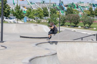 Patenciler ve motorcular numaralarını güneşli bir yaz gününde halka açık olan açık bir kaykay parkında yapıyorlar.