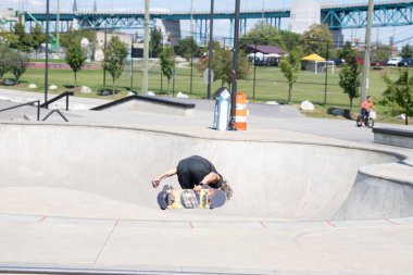 Patenciler ve motorcular numaralarını güneşli bir yaz gününde halka açık olan açık bir kaykay parkında yapıyorlar.