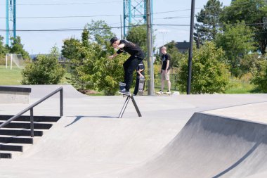 Patenciler ve motorcular numaralarını güneşli bir yaz gününde halka açık olan açık bir kaykay parkında yapıyorlar.