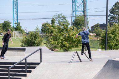 Patenciler ve motorcular numaralarını güneşli bir yaz gününde halka açık olan açık bir kaykay parkında yapıyorlar.