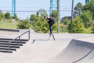 Patenciler ve motorcular numaralarını güneşli bir yaz gününde halka açık olan açık bir kaykay parkında yapıyorlar.