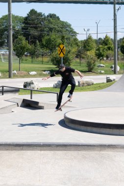 Patenciler ve motorcular numaralarını güneşli bir yaz gününde halka açık olan açık bir kaykay parkında yapıyorlar.