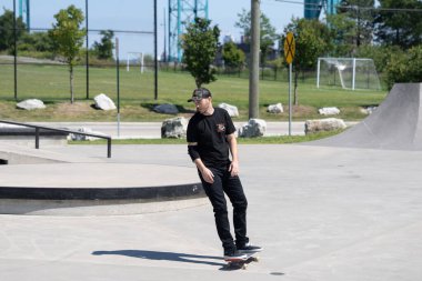 Patenciler ve motorcular numaralarını güneşli bir yaz gününde halka açık olan açık bir kaykay parkında yapıyorlar.