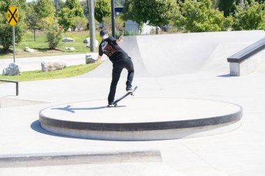 Patenciler ve motorcular numaralarını güneşli bir yaz gününde halka açık olan açık bir kaykay parkında yapıyorlar.
