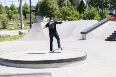Patenciler ve motorcular numaralarını güneşli bir yaz gününde halka açık olan açık bir kaykay parkında yapıyorlar.