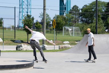 Patenciler ve motorcular numaralarını güneşli bir yaz gününde halka açık olan açık bir kaykay parkında yapıyorlar.