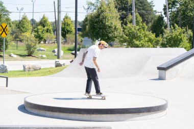 Patenciler ve motorcular numaralarını güneşli bir yaz gününde halka açık olan açık bir kaykay parkında yapıyorlar.