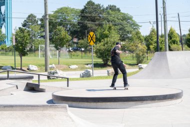 Patenciler ve motorcular numaralarını güneşli bir yaz gününde halka açık olan açık bir kaykay parkında yapıyorlar.