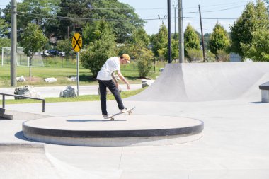 Patenciler ve motorcular numaralarını güneşli bir yaz gününde halka açık olan açık bir kaykay parkında yapıyorlar.