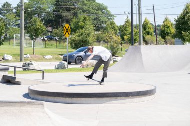 Patenciler ve motorcular numaralarını güneşli bir yaz gününde halka açık olan açık bir kaykay parkında yapıyorlar.
