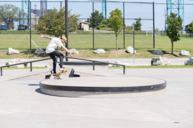 Patenciler ve motorcular numaralarını güneşli bir yaz gününde halka açık olan açık bir kaykay parkında yapıyorlar.