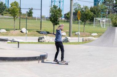 Patenciler ve motorcular numaralarını güneşli bir yaz gününde halka açık olan açık bir kaykay parkında yapıyorlar.