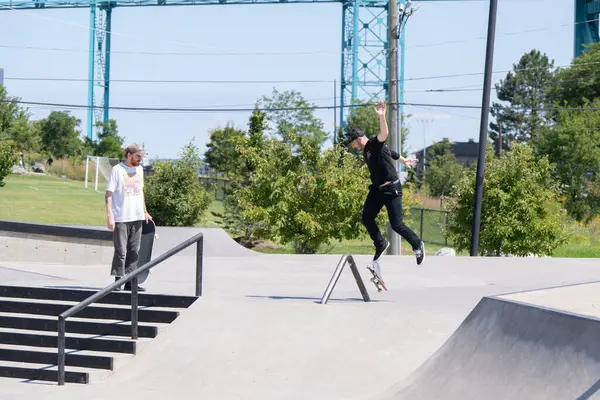 Patenciler ve motorcular numaralarını güneşli bir yaz gününde halka açık olan açık bir kaykay parkında yapıyorlar.