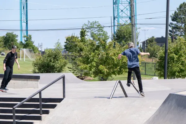 Patenciler ve motorcular numaralarını güneşli bir yaz gününde halka açık olan açık bir kaykay parkında yapıyorlar.