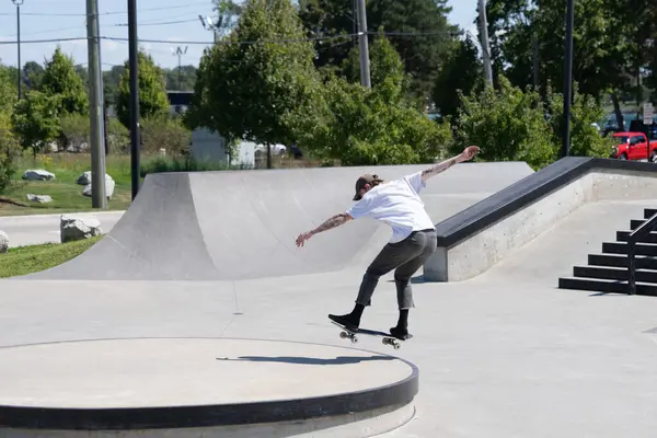 Patenciler ve motorcular numaralarını güneşli bir yaz gününde halka açık olan açık bir kaykay parkında yapıyorlar.