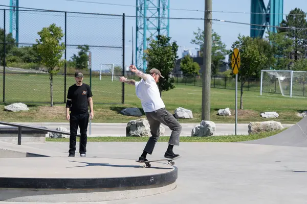 Patenciler ve motorcular numaralarını güneşli bir yaz gününde halka açık olan açık bir kaykay parkında yapıyorlar.