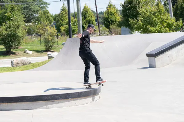 Patenciler ve motorcular numaralarını güneşli bir yaz gününde halka açık olan açık bir kaykay parkında yapıyorlar.