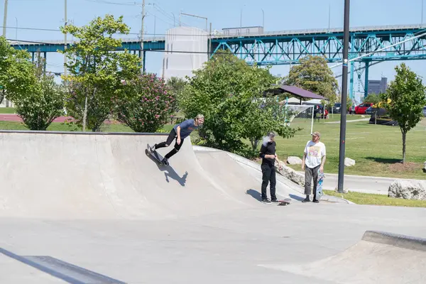 Patenciler ve motorcular numaralarını güneşli bir yaz gününde halka açık olan açık bir kaykay parkında yapıyorlar.